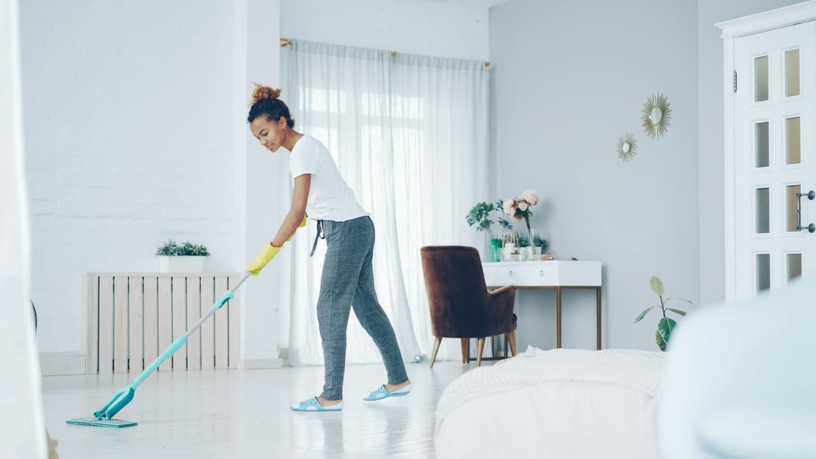 A cleaner mopping the floor of a bright living room
