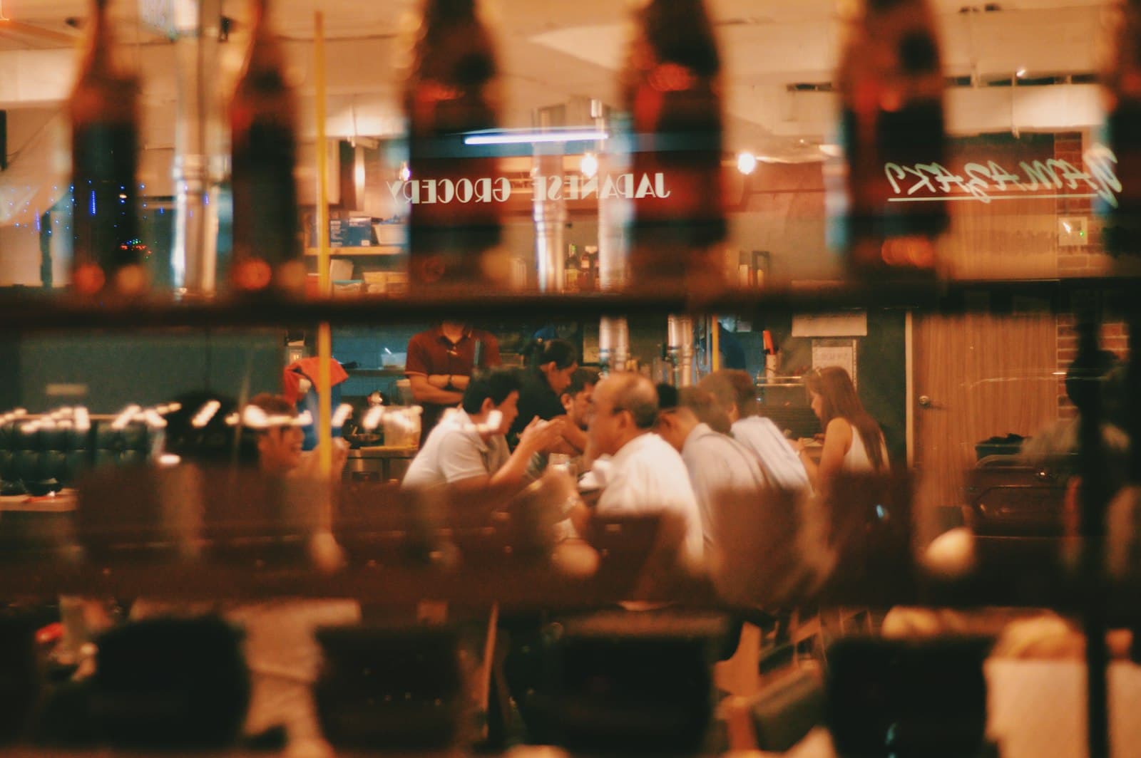 A busy restaurant dining room at night, seen through the window