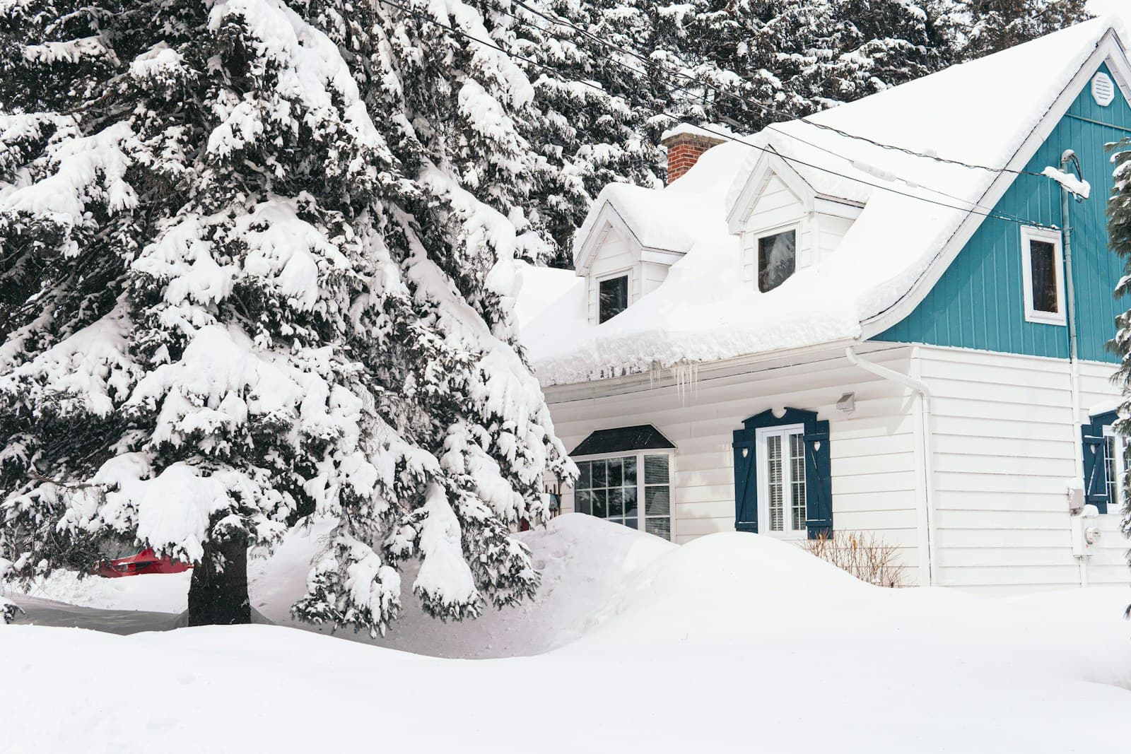 A blue and white house half buried in snow on a winter day